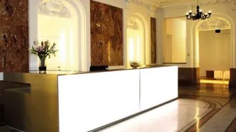 Elegante Empfangshalle mit modernem Tresen, Marmorboden und klassischer Deckenbeleuchtung, die einen luxuriösen Eindruck vermittelt.