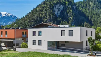 Modernes Gebäude mit Rampe und Bergblick unter blauem Himmel.