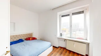Helles Schlafzimmer mit Holzboden, einem Doppelbett und einem Fenster mit Blick nach draußen.