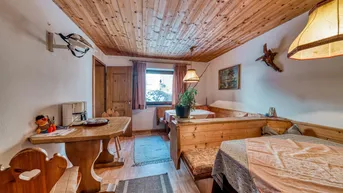 Gemütlicher Essbereich im alpinen Stil mit Holztäfelung an Decke und Wänden sowie traditionellen Sitzbänken.
