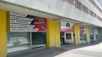 Fassade eines Geschäftsgebäudes mit Werbeschildern für einen Outlet-Laden und Zugang über eine Rampe.
