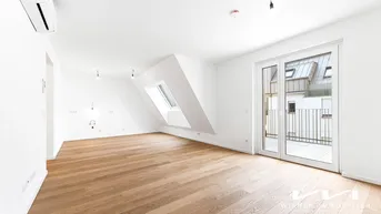 Heller Wohnbereich mit Eichenparkett, Dachschräge, Dachfenster und Zugang zum Balkon.