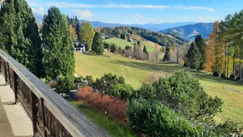Geräumiger Balkon mit Holzbalkonbrüstung und weitem Blick auf die grüne Berglandschaft.