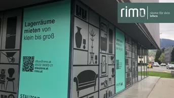 Gebäudefassade mit großflächiger Werbung für Lagerräume und Kontaktinformationen an den Fenstern.