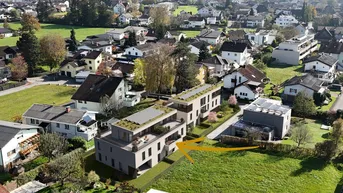 Luftaufnahme eines Neubauprojekts in einer grünen Wohngegend mit umliegenden Häusern und Bergblick.