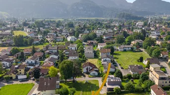 Luftaufnahme eines Baugrundstücks in einer ruhigen Wohngegend mit Bergblick und viel Grün.