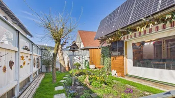 Gepflegter Garten mit Hochbeeten, Rasenfläche und Solaranlage auf dem Dach.