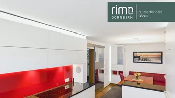 Moderne Küche mit weißen Schränken, roter Rückwand und integriertem Essbereich.