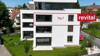 Moderne Neubau-Wohnanlage mit weißer Fassade, großen Fenstern und begrünten Außenbereichen.