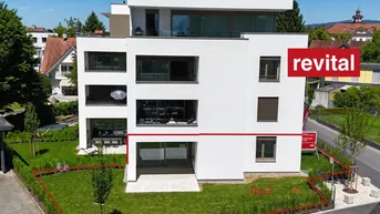Moderne Neubau-Wohnanlage mit weißer Fassade, großen Fenstern und umliegendem Garten.