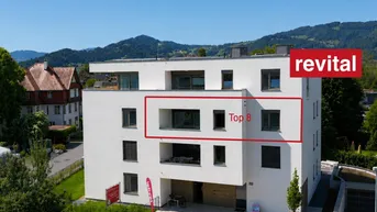 Moderne Wohnanlage mit weißer Fassade, Balkonen und Bergblick in grüner Umgebung.