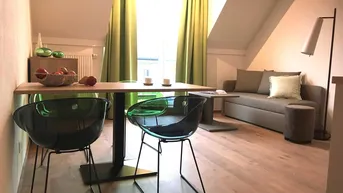 Helles Wohn- und Esszimmer mit Dachschrägen, modernem Mobiliar und Zugang zu einem Fenster.