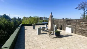 Weitläufige Dachterrasse mit Fliesenboden, Gartenmöbeln und weitem Blick in die Umgebung.