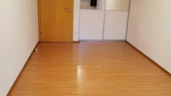Leeres Zimmer mit Laminatboden und integriertem Spiegelschrank, ideal als Schlaf- oder Arbeitszimmer.