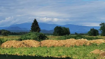 Weitläufiger Blick auf die umliegende Landschaft mit Bergen und Feldern unter blauem Himmel.