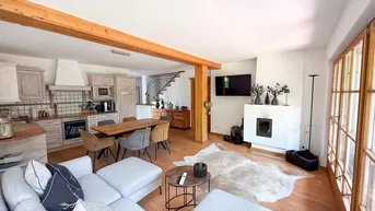 Geräumiger offener Wohn- und Essbereich mit integrierter Küche, Holzbalken und Kamin.