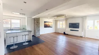 Offener Wohnbereich mit Holzboden, integrierter Küche und Steinwandakzent, hell und modern.