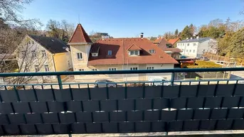 Blick vom Balkon auf die umliegenden Wohnhäuser und grüne Umgebung an einem sonnigen Tag.