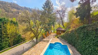 Außenbereich mit privatem Pool, umgeben von grünen Hügeln und Bäumen unter blauem Himmel.