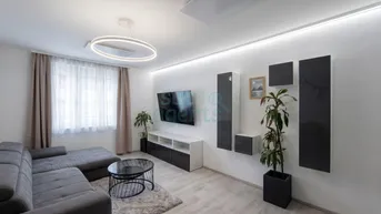 Modernes Wohnzimmer mit bequemer Couch, Fernseher und indirekter Beleuchtung an den Wänden.
