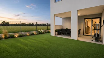 Moderne Terrasse mit Rasenfläche, Essbereich im Freien und Blick auf grüne Felder.