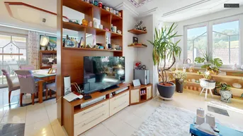 Gemütlicher Wohnbereich mit Fernseher, vielen Pflanzen und Blick ins Grüne.