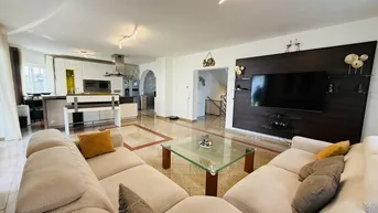 Geräumiger offener Wohnbereich mit bequemer Couch, Fliesenboden und integrierter Küche im Hintergrund.