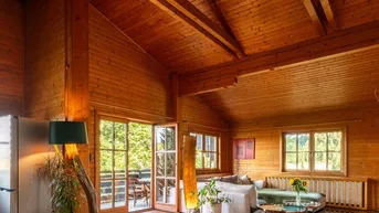 Geräumiges Wohnzimmer im Chalet-Stil mit Holzwänden, hohen Decken und Zugang zur Terrasse.