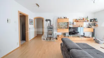 Geräumiges Wohnzimmer mit Holzboden, Kaminofen und Holzmöbeln.