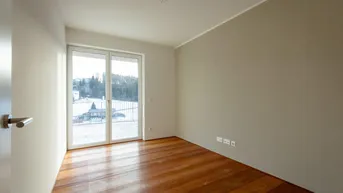 Lichtdurchflutetes Schlafzimmer mit Holzboden und Zugang zum französischen Balkon.