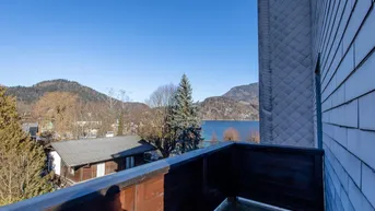 Balkon mit Holzboden und Geländer bietet einen weiten Blick auf den See und die umliegenden Berge.