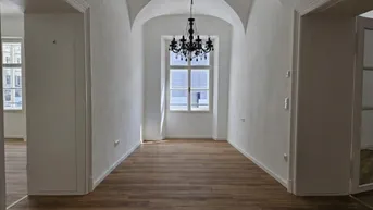 Heller Flur mit Gewölbedecke, Holzboden und einem eleganten Kronleuchter.