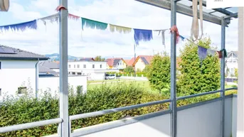 Überdachter Balkon mit weitem Blick über die Wohnsiedlung und die grüne Umgebung.