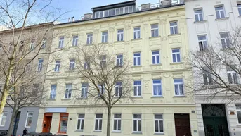 Historisches Gebäude mit gelber Fassade und vielen Fenstern an einer städtischen Straße.