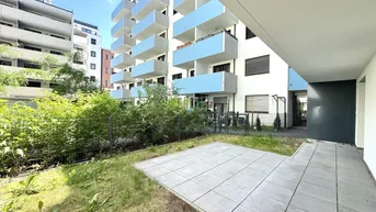 Moderne Wohnanlage mit hellblauen Balkonen und einer kleinen Terrasse im Erdgeschoss mit Grünfläche.