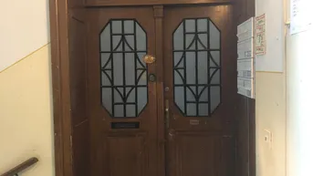 Eingangsbereich mit einer traditionellen Holztür, verziert mit Glaseinsätzen und Oberlicht.