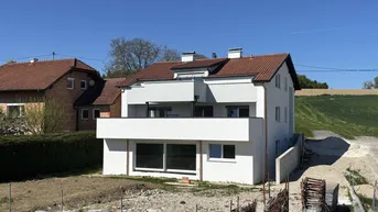 Neubau-Doppelhaushälfte mit moderner Architektur und Balkonen in ländlicher Umgebung.