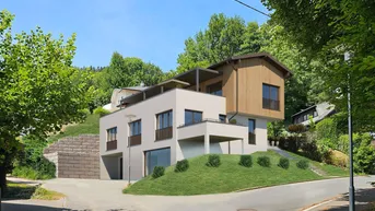 Moderne Architektur eines Neubaus in Hanglage, umgeben von üppigem Grün und Bäumen.