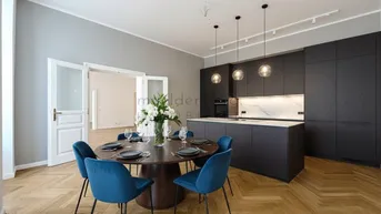 Moderne offene Küche mit dunklen Schränken, Marmorarbeitsplatte und Essbereich mit Fischgrätparkett.