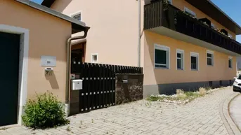 Ansicht des Gebäudes von außen mit gepflasterter Zufahrt und einem Nebengebäude.