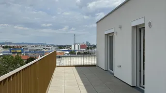 Große Dachterrasse mit Fliesenboden und weitem Blick über die Stadtlandschaft unter blauem Himmel.