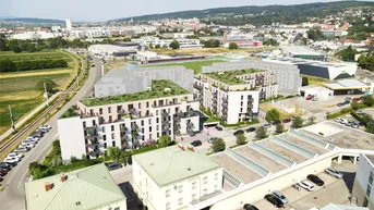 Luftaufnahme eines modernen Wohnkomplexes mit begrünten Dächern und Balkonen in städtischer Umgebung.