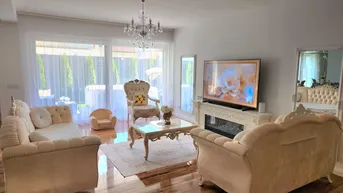 Elegantes Wohnzimmer mit beigen Sofas, Kamin und großem Fernseher.