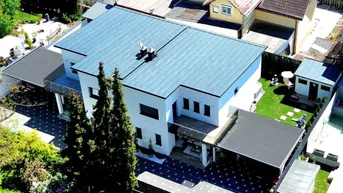 Luftaufnahme eines modernen Einfamilienhauses mit Flachdach und gepflegtem Gartenbereich.