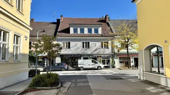 Blick auf eine belebte Straße mit Gebäuden, die Geschäfte im Erdgeschoss beherbergen.