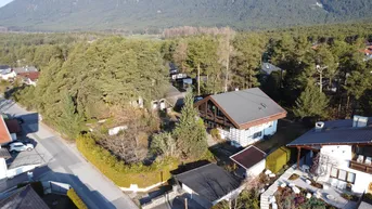 Drohnenaufnahme eines Hauses mit Satteldach, umgeben von Bäumen und anderen Wohnhäusern in einer ländlichen Umgebung.