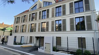Modernes Mehrfamilienhaus mit mehreren Etagen, großen Fenstern und Fensterläden.