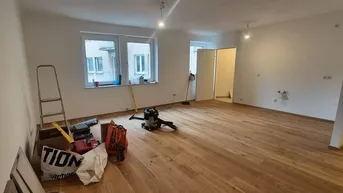 Helles, unmöbliertes Zimmer mit neuem Holzfußboden und Blick nach draußen, bereit zur Fertigstellung.