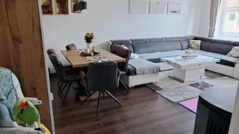 Geräumiger Wohn- und Essbereich mit dunklem Holzboden, großem Sofa und Esstisch.