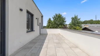 Geräumige Dachterrasse mit hellen Fliesen und weitem Blick in die Umgebung.